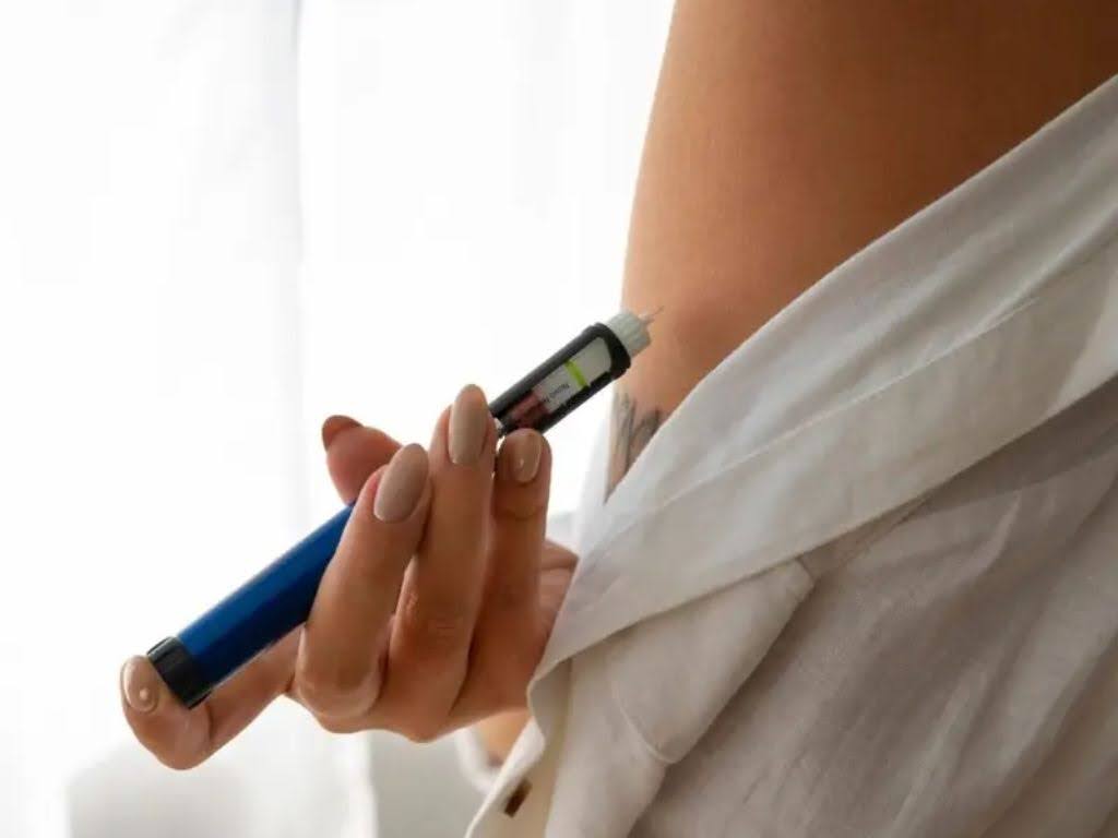 Person administering GLP-1 medication via injection, emphasizing weight loss and metabolic health in Omaha fitness context.