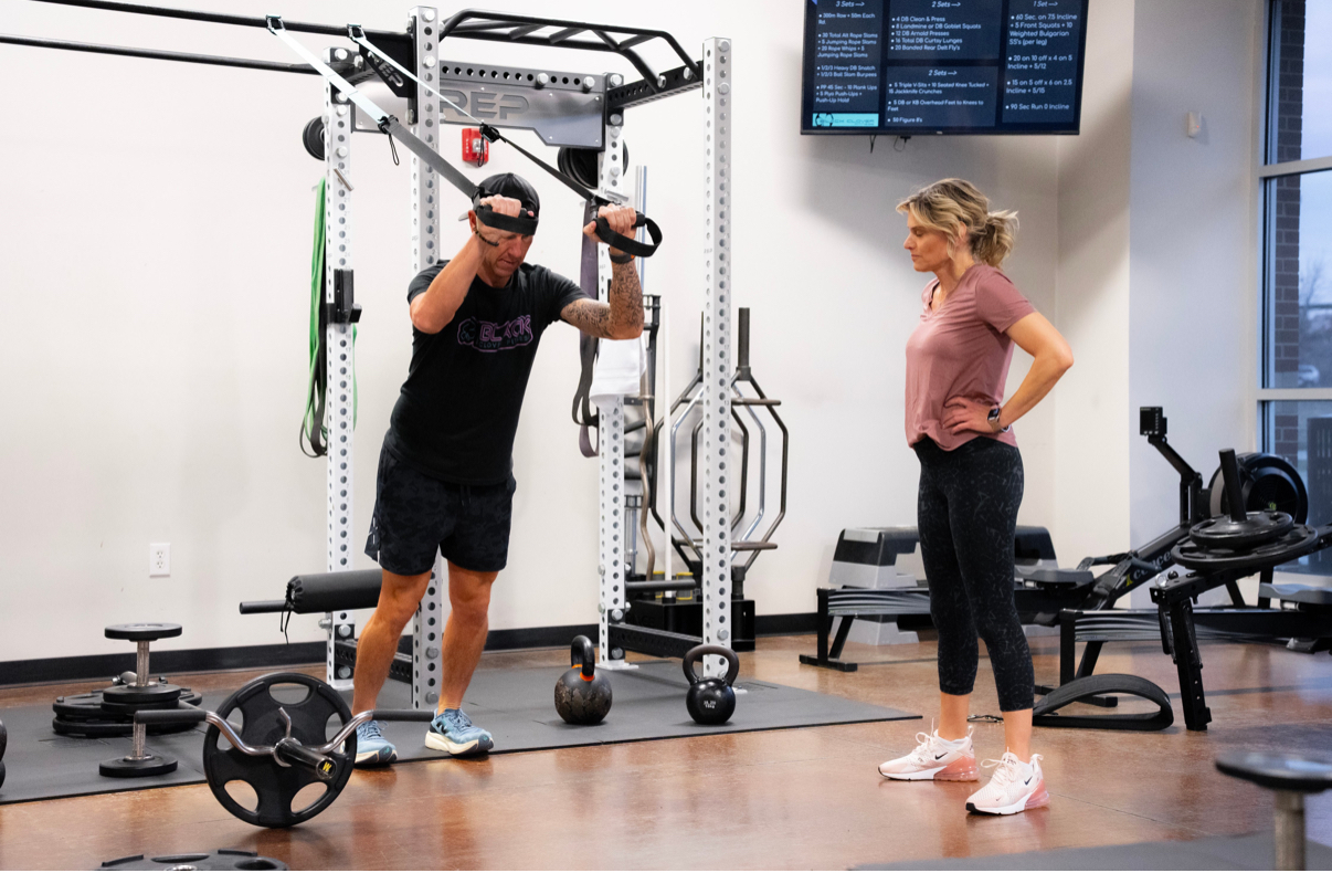 Coach cueing squat technique with a semi-private personal training client at BCF